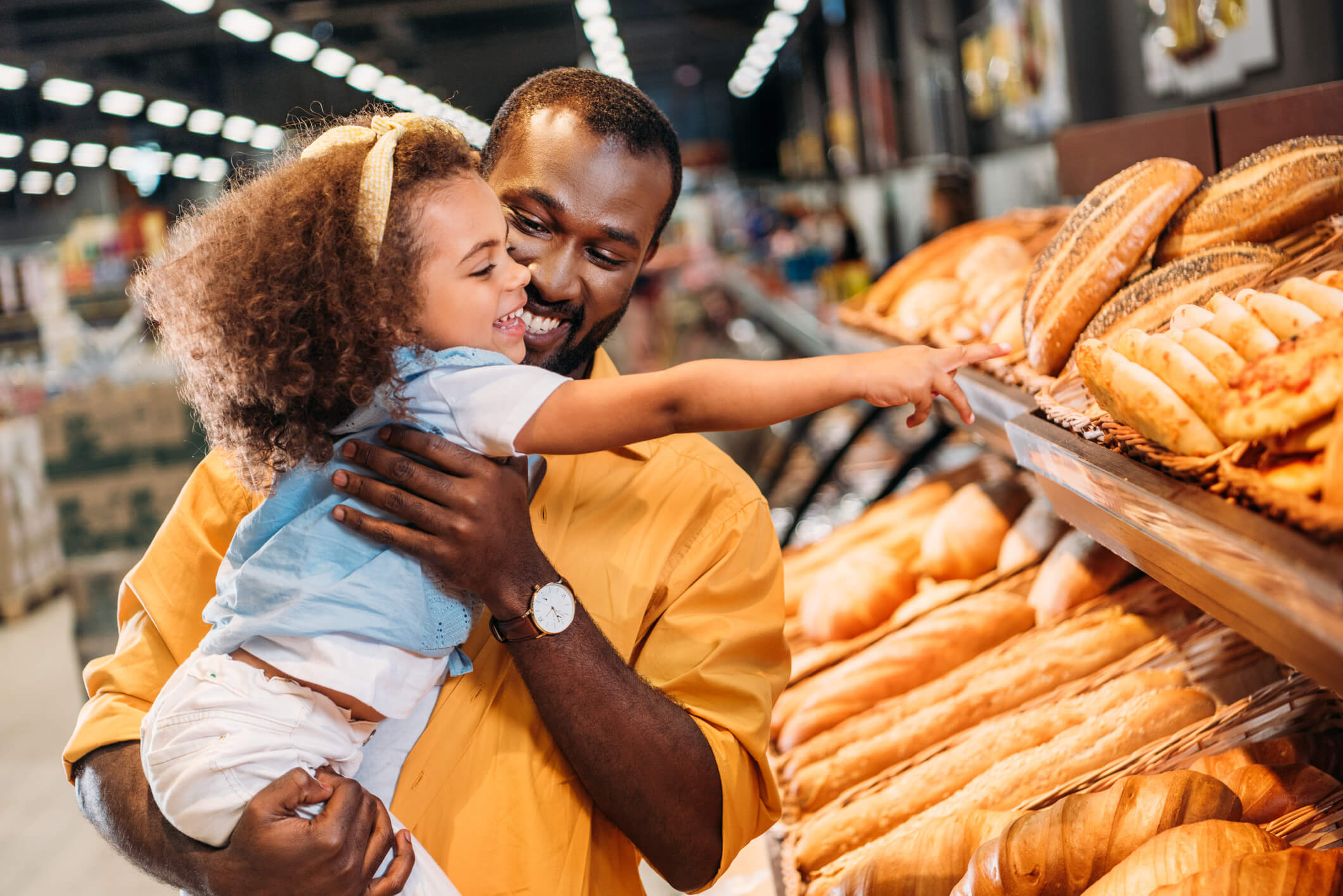 child pointing by finger at pastry to father in supermarket